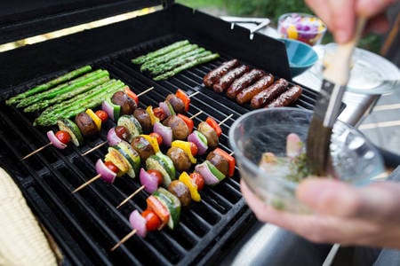 Man Braising Vegetable Skewers on a BBQ Grill with a Brush