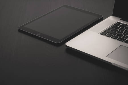 View of a Tablet and a Laptop on a Black Table
