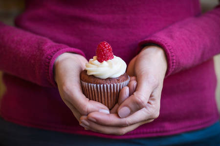 Close-Up View of a Woman Holding a Cupcake in Both Hands