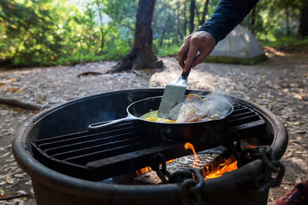 Man's Hand Using Metal Spatula to Cook Breakfast on a Fire Pit
