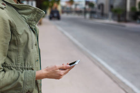 Woman Standing on a Street Holding a Cell Phone