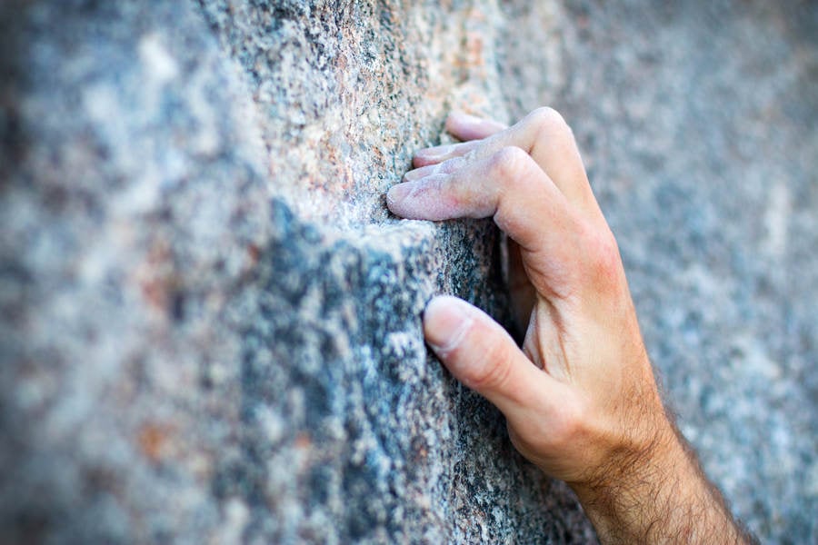 Close-Up of a Climber's Hand Crimping a Narrow Granite Hold Stock Photo