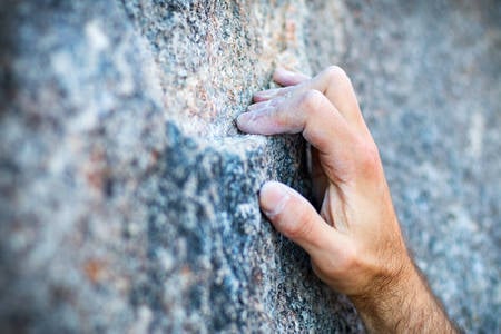Close-Up of a Climber's Hand Crimping a Narrow Granite Hold