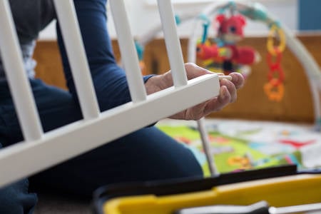 Close-Up of a Man Assembling a Baby Crib in a Children's Room