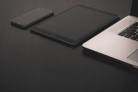 View of a Tablet, Cell Phone and a Laptop on a Black Table