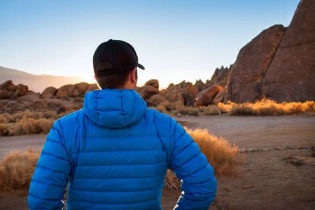 Man Looking Towards Rocks in a Desert at Sunrise