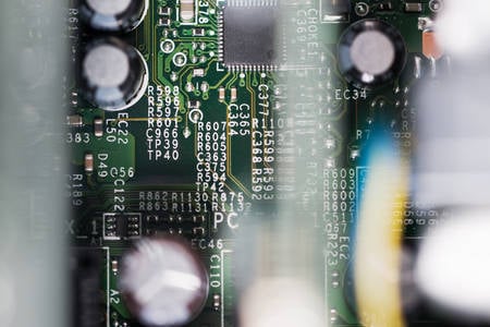 Close-Up View of a Green Circuit Board with Blurred Parts in Foreground