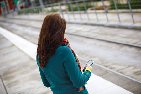 High-Angle View of a Woman Standing on a Platform Checking Her Phone