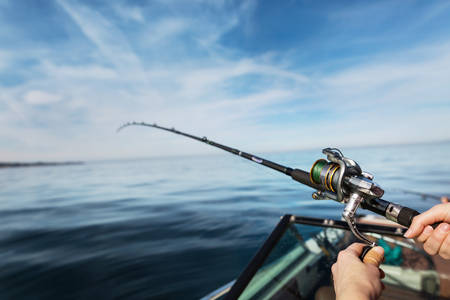Hands Holding a Fishing Rod on a Boat in the Ocean