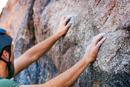 Climber with His Hands on a Rock Ready for the Climb