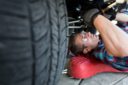 Auto Mechanic Laying on a Creeper Working Underneath the Front of a Truck