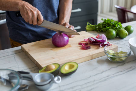  Man Cutting an Onion on a Wooden Board in a Kitchen