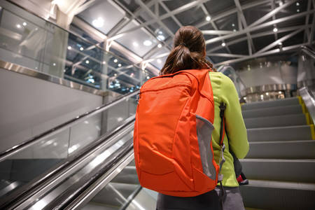 Detailed View of a Woman with a Backpack Going up an Escalator at the Airport
