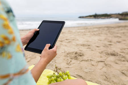Young Woman Holding a Tablet on a Sandy Beach