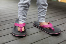 Feet of a Toddler Girl Wearing Her Mom's Pink Flip-Flops