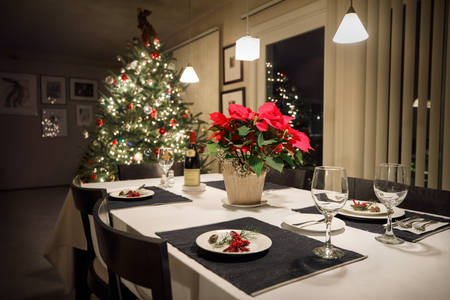 Festive Holiday Table Setting with a Lit Christmas Tree in the Background