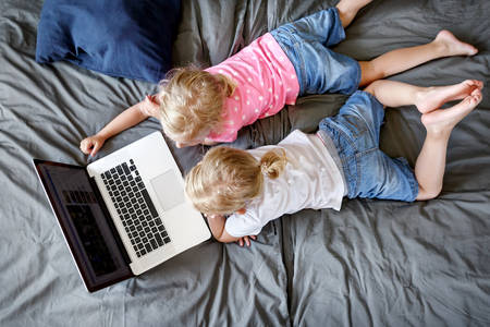 Overhead View of Little Twin Sisters in a Bed Watching a Movie on a Laptop