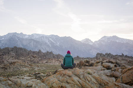 Rear View of a Woman Sitting on a Rock and Looking at Mountains