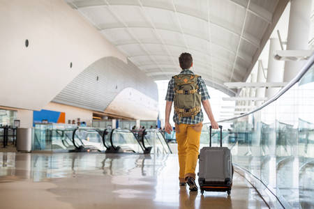 Traveler with a Backpack Pulling a Luggage Through an Airpot Lobby