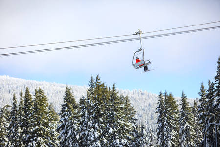 Single Skier Sitting on a Chairlift Going up the Mountain