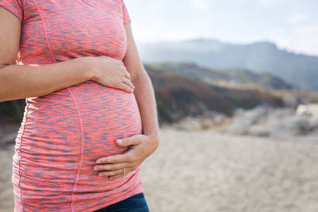 Close-Up of a Pregnant Woman Standing on a Beach and Holding Her Belly