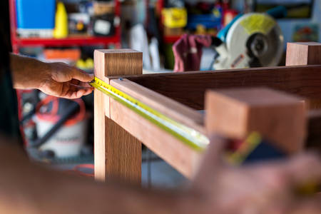 Handyman Measuring Wooden Planter Construction in a Workshop