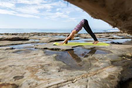 Girl Practicing Yoga a Downward-Facing Dog Pose by the Ocean