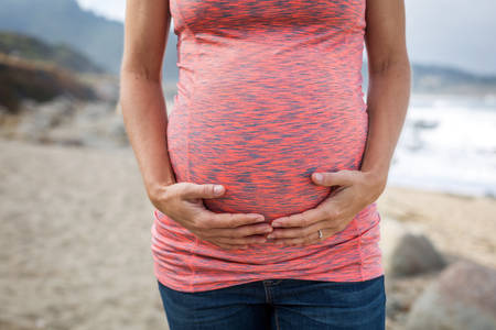 Close-Up of a Pregnant Woman Standing on a Beach and Holding Her Bump