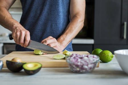  Man Cutting a Lime on a Wooden Board in a Kitchen
