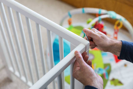 Man Assembling a Baby Crib in a Children's Room