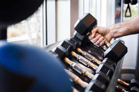 Close-Up of a Man Taking Dumbbells from a Rack in a Gym