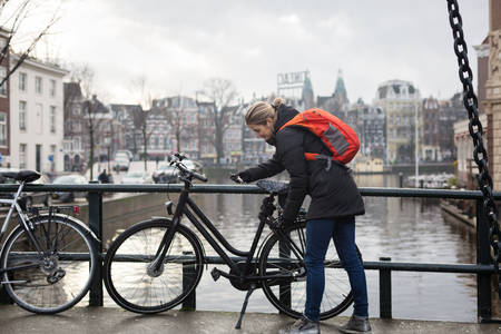 View of a Woman Locking a Bicycle on a City Bridge