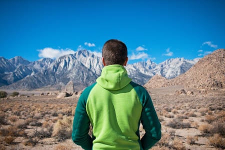Man Standing in the Desert Facing High Mountains