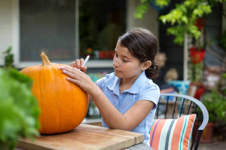 View of a Young Girl Drawing on a Pumpkin