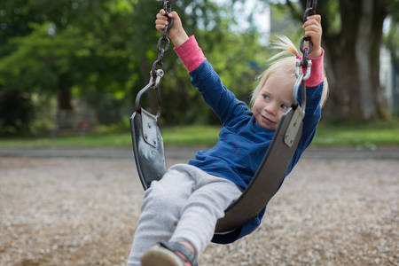 View of a Toddler Girl Sitting on a Swing at Playground