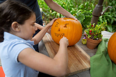Young Girl Carving a Pumpkin with Her Mom