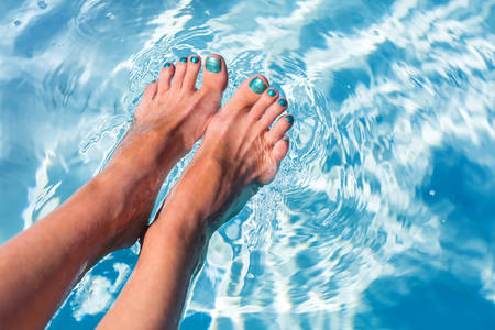 Close-Up of Woman's Feet with Turquoise Toenails in a Pool 