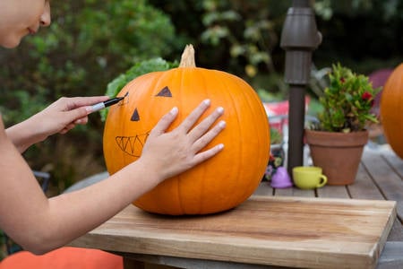 Young Girl Drawing on a Pumpkin Before Carving