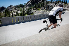 Man Riding a Bicycle on a Bridge in the Mountains 