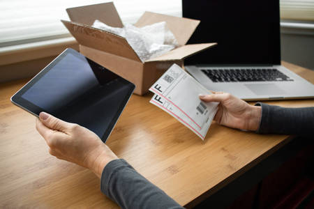 Woman Holding a Tablet in Her Hand While Preparing Shipping Labels