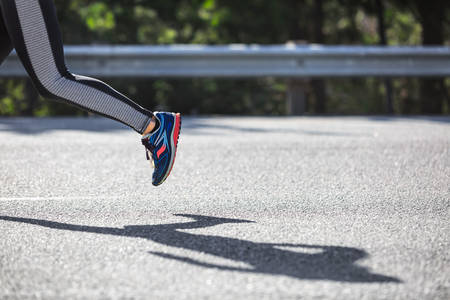 Lower Section of a Long-Distance Runner Running on a Road