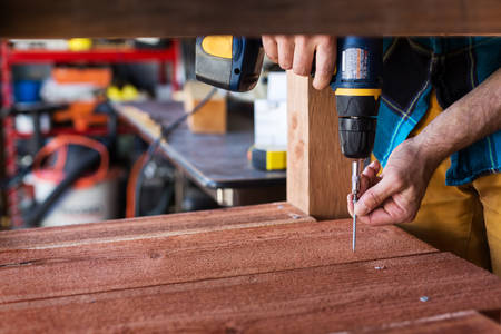 Handyman Using an Electric Screwdriver in a Workshop