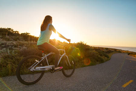 Girl on a Late Afternoon Cruiser Bike Ride on an Ocean Coast