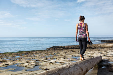 Carefree Athletic Woman Walking on a Tree Log on a Beach