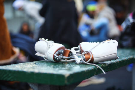 Close-Up of White Women's Ice Skates Laying on a Bench