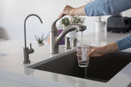 Woman Filling a Glass with Tap Water in a Kitchen
