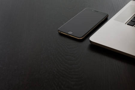 View of a Cell Phone and Laptop on a Black Table