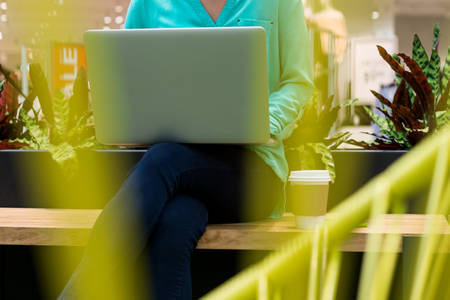 Young Woman with Laptop Sitting on a Bench in a Shopping Mall
