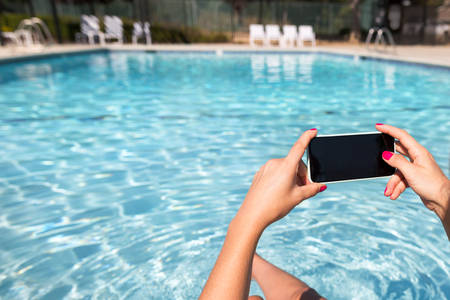 Hands of a Woman Siting by Pool and Taking Pictures With a Smartphone
