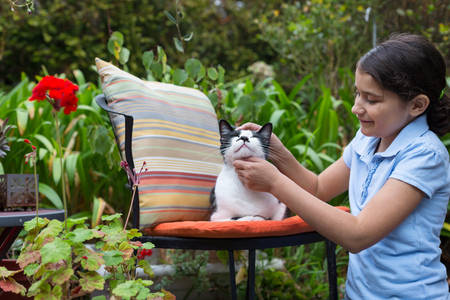 Smiling Young Girl Stroking a Cat Outdoors